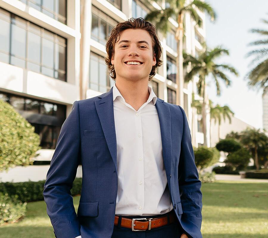 a male student standing outside of a building on campus at Palm Beach Atlantic University